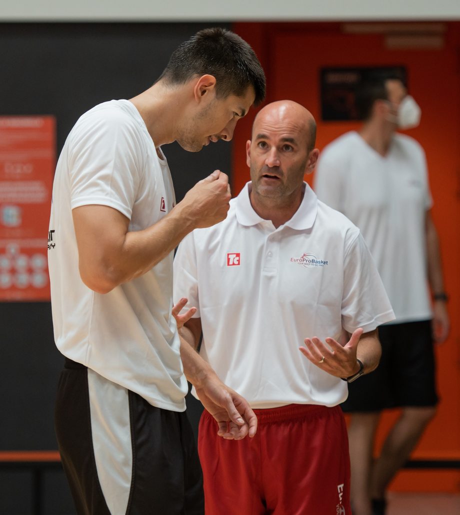 Coach Dave Love explaining an idea to a player in the gym