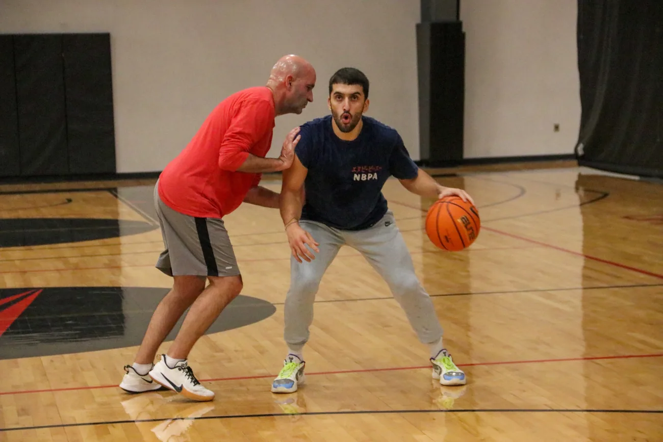 Coach Dave Love pushing NBA guard Facundo Campazzo off his base during a balance push drill while Campazzo holds a low, athletic shooting stance.