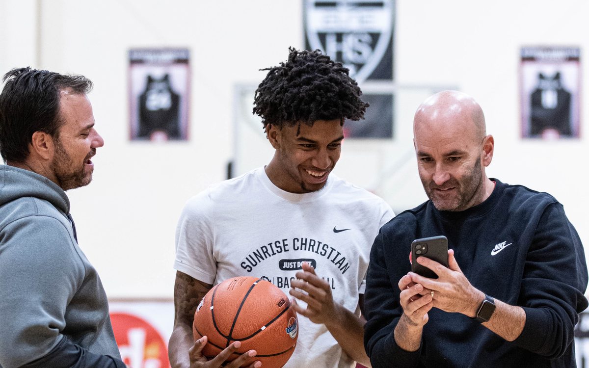 Coach Dave Love reviewing video on a phone with a coach and player